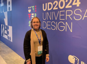 Ira Verma standind in front of conference logo that says UD2024 Universal Design